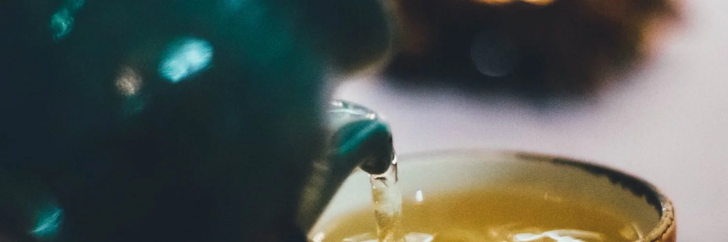person pouring liquid into brown ceramic cup