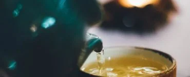 person pouring liquid into brown ceramic cup