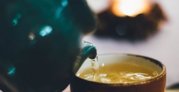 person pouring liquid into brown ceramic cup