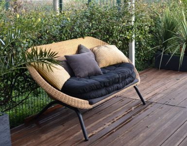 cozy rattan sofa with cushions in tropical garden