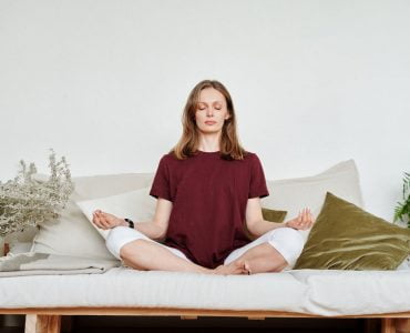 woman in red shirt sitting on couch meditating