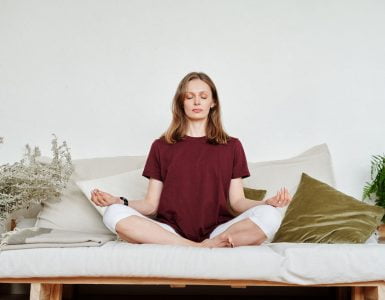 woman in red shirt sitting on couch meditating