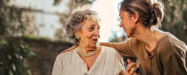 joyful adult daughter greeting happy surprised senior mother in garden