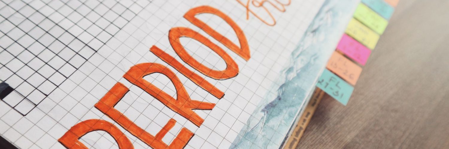 Handgeschreven menstruatiekalender in een notitieboek met ruitjespapier om de cyclus bij te houden