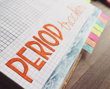 Handgeschreven menstruatiekalender in een notitieboek met ruitjespapier om de cyclus bij te houden